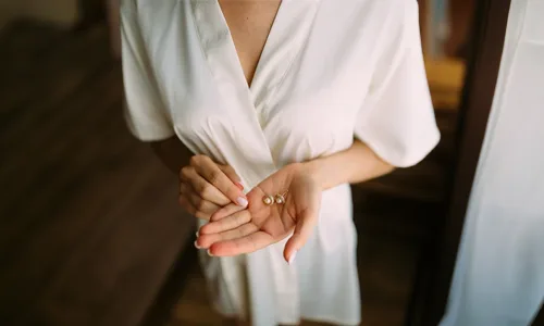Women in white dress with earrings in hand