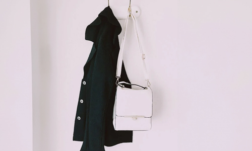 white-handbag-and-black-coat-in-hanger