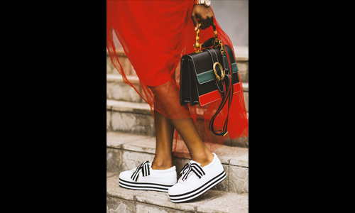 Woman in red dress, white shoes and black bag